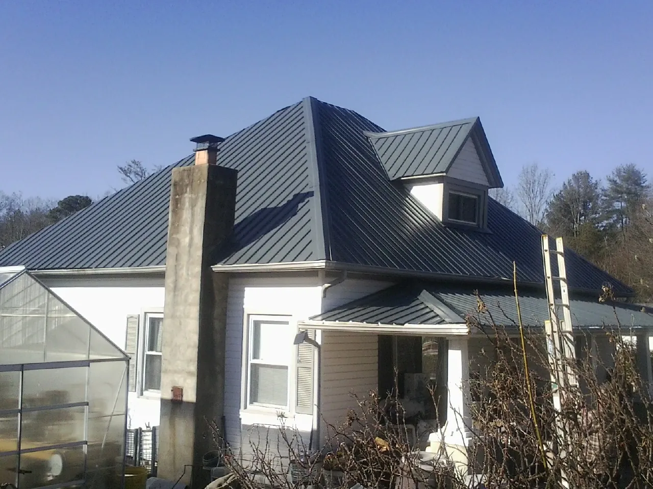Dark blue standing seam metal roof on a white farmhouse with dormer — Slate & Tile Roof Repair by Roofing Brothers in Kamas