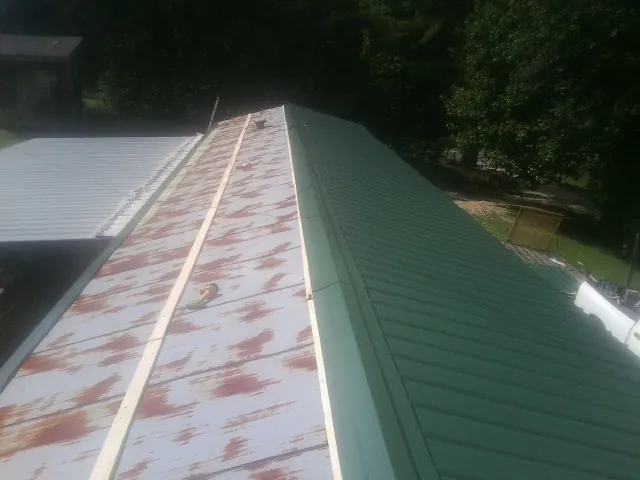 Old rusted panels beside newly installed green metal roofing — Wind Damage Roof Repair by Roofing Brothers in Kamas