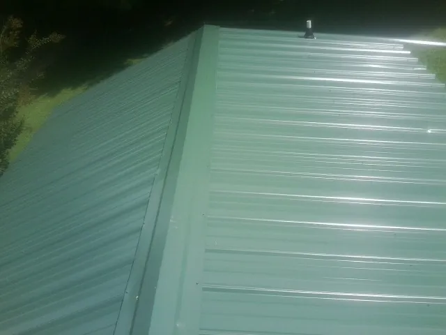 New green metal panels meeting at the ridge of a roof — Flat Roof Repair work by our crew in Kamas