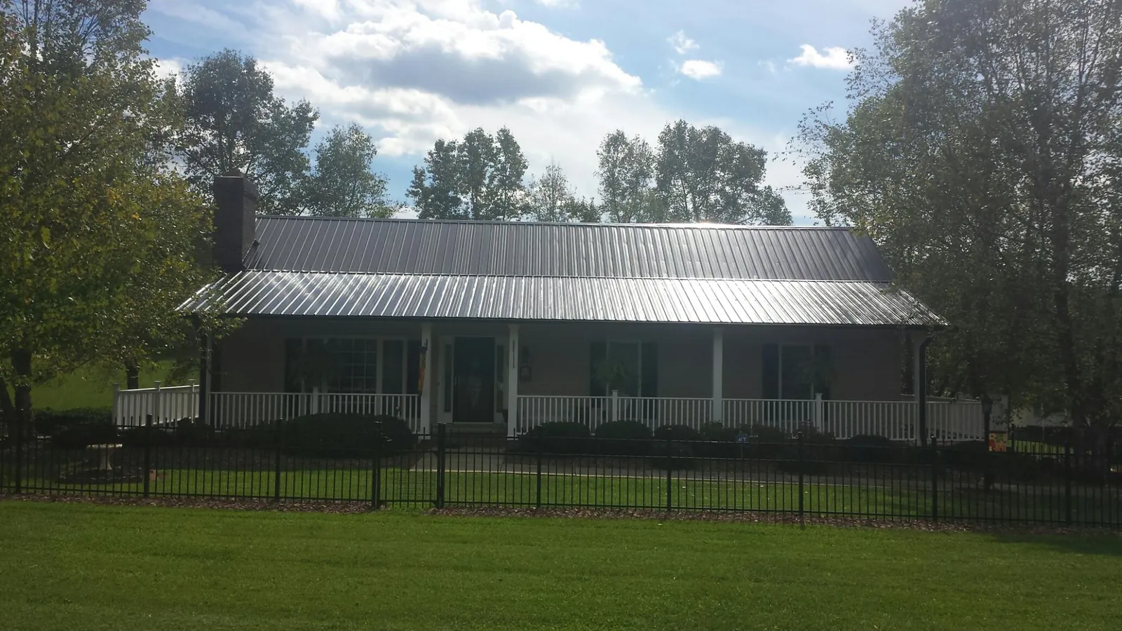 Gray metal roof on a brick ranch with a full width front porch — Gutter Guard Installation work by our crew in Kamas