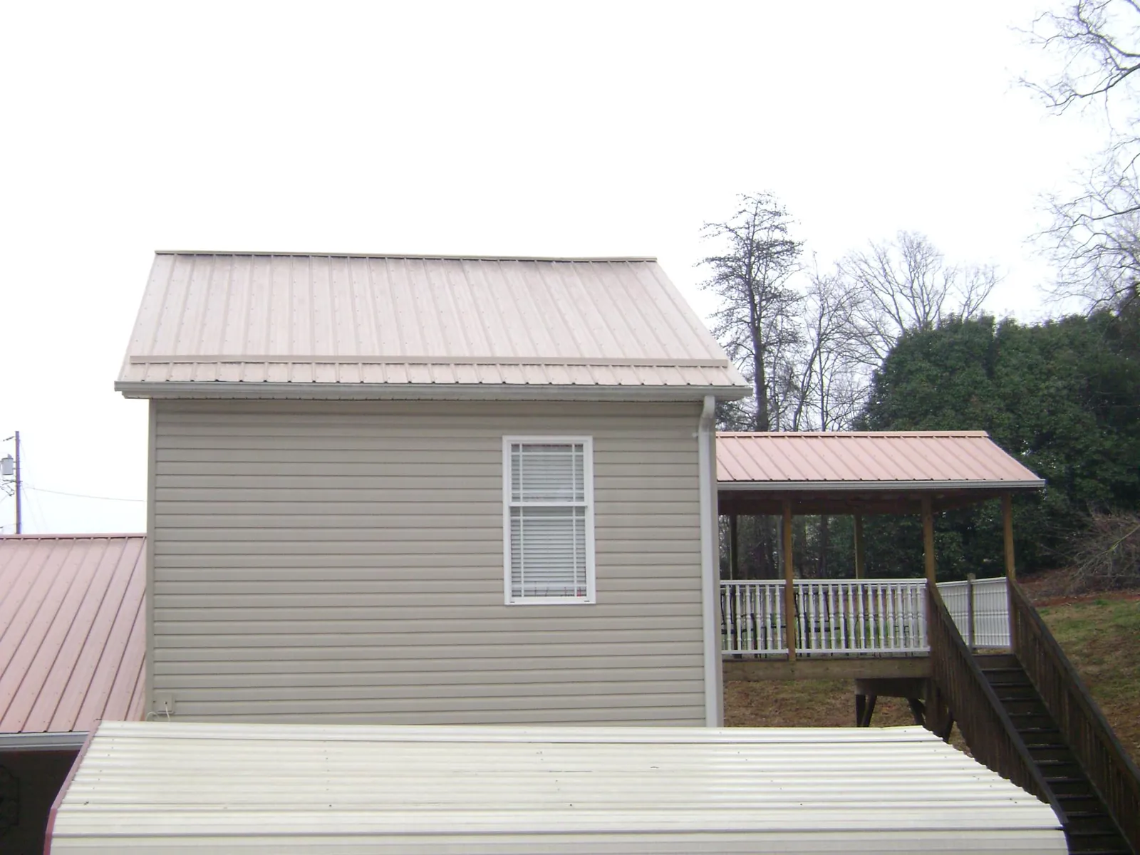 Tan metal roofs on a two story addition and attached porch, from a Roof Replacement job in Kamas